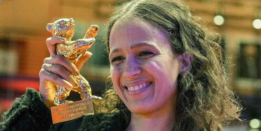 Mati Diop hält lächelnd den Goldenen Bären in die Kamera