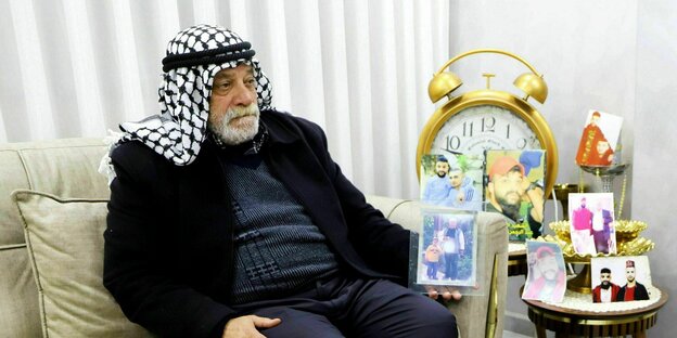 Bassem Al-Bahash sitzt auf dem Sofa in seinem Wohnzimmer und hält ein Foto seines Sohnes in der Hand