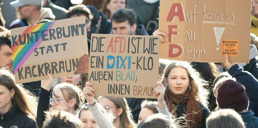 Menschen stehen mit Pappschildern auf der Straße