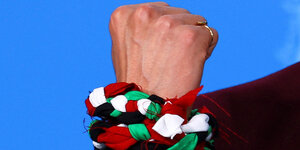 Eine Hand eingewickelt mit einem Armband auf der palästinensischen Flagge