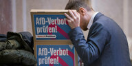 Ein Mann schaut in einen Karton, auf dem steht: "AfD-Verbot prüfen!"