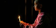 Ein Mädchen hält zum Gedenken eine Kerze in der Hand