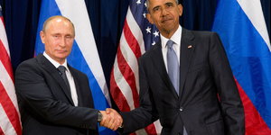 Putin und Obama schütteln sich die Hand vor Flaggen