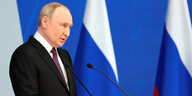 Putin steht an einem Rednerpult. er ist ein Alter Mann mit aufgedunsenem geyicht und lichtem Haar. Er trägt einen dunklen Anzug und ein helles Hemd.