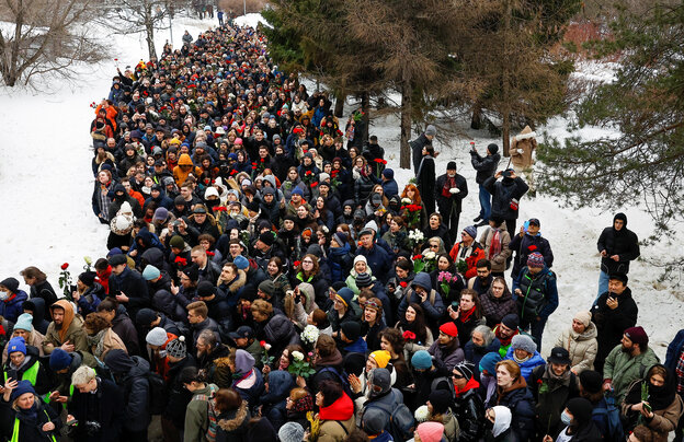Viele Menschen laufen mit blumen in einer Prozession durch den Schnee zum Borissowo-Friedhof, auf dem Nawalny beerdigt wird