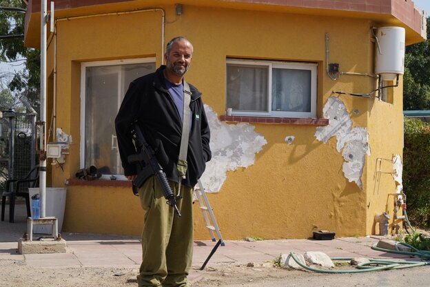 Ein Mann mit Waffe steht vor einem Haus