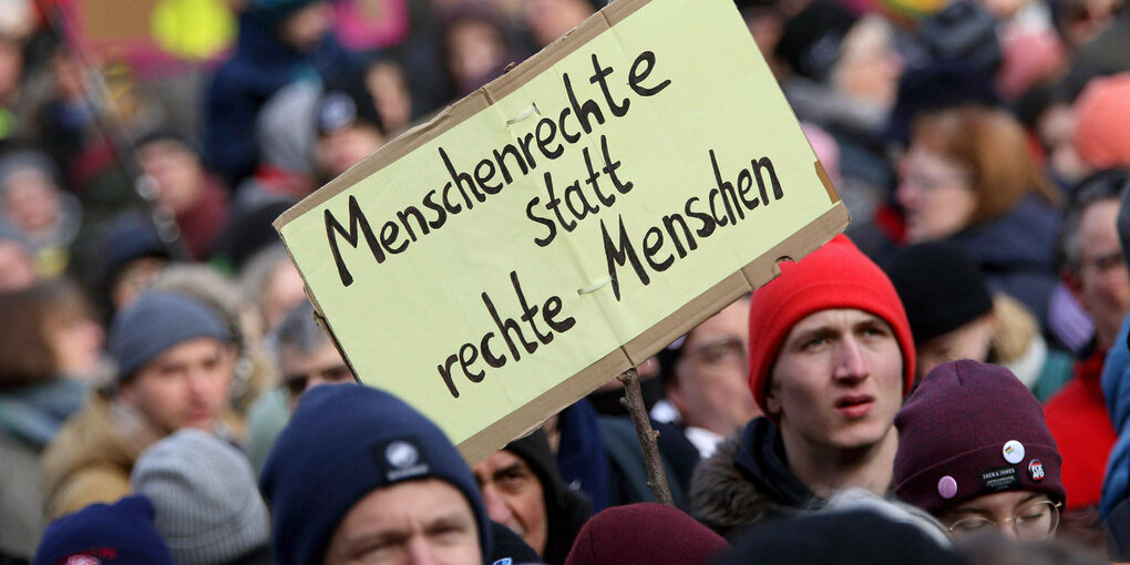 Eine Menschenmenge auf einer Demonstration. In der Mitte ein Schild "Menschenrechte statt rechte Menschen".