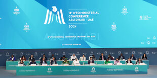 Ein Foto der WTO-Konferenz in Abu-Dhabi. Man sieht Menschen auf einem Podium sitzen.