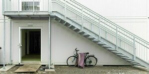 Ein Fahrrad steht vor einem weißen Container Häuschen