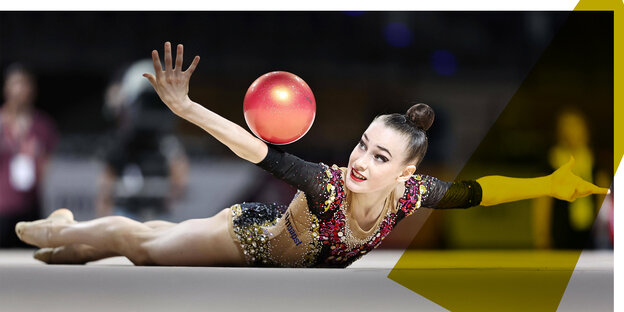 Die Gymnastin Darfa Varfolomeev turnt mit einem roten Ball am Boden.