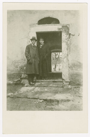 Schwarz-Weiß-Foto von Franz Kafka (rechts im Bild) und Ottla Kafka (links). Die beiden Geschwister stehen vor der Tür eines alten Hofs, die Wände sind teils abgebröckelt. Franz Kafka trägt einen Mantel, Krawatte und Hut. Ottla Kafka trägt einen dunklen Ma