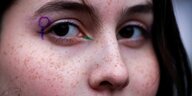 Eine Frau hat sich das Frauenzeichen in den Augenwinkel gemalt