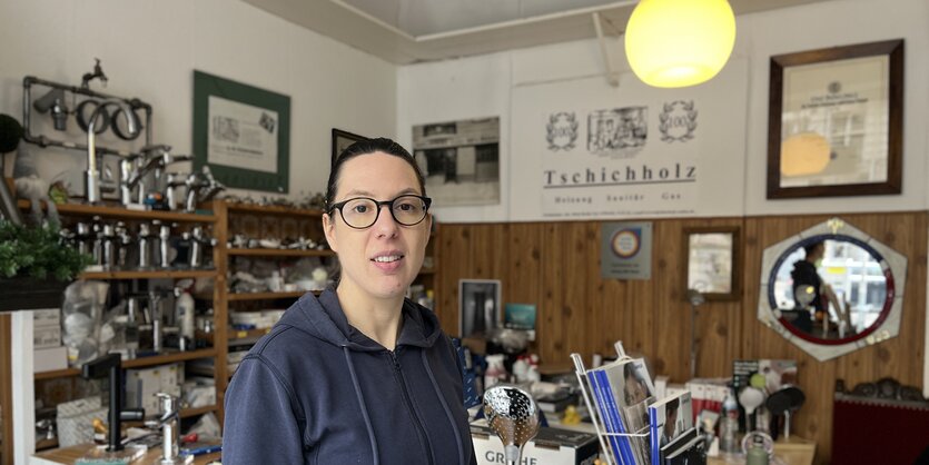 Andrea Tschichholz, Anlagemechanikerin im SHK-Bereich, steht in ihrem Büro. Im Hintergrund sind Armaturen und Bilder von der Firma aus dem Gründungsjahr 1903 zu sehen.