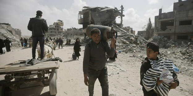 Palästinser mit geborgenem Hab und Gut nach dem Aufsuchen ihrer zerstörten Häuser in der Stadt Khan Younis am Dienstag