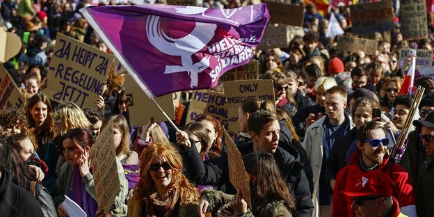 Demonstrierende mit lila Fahne bei einer Marsch zum Frauentag am 8. März 2024 in Berlin