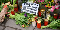 Zwischen Blumen und Grablichtern liegt eine Zettel, auf dem steht "Tauer über das fehlende Waffenverbot"