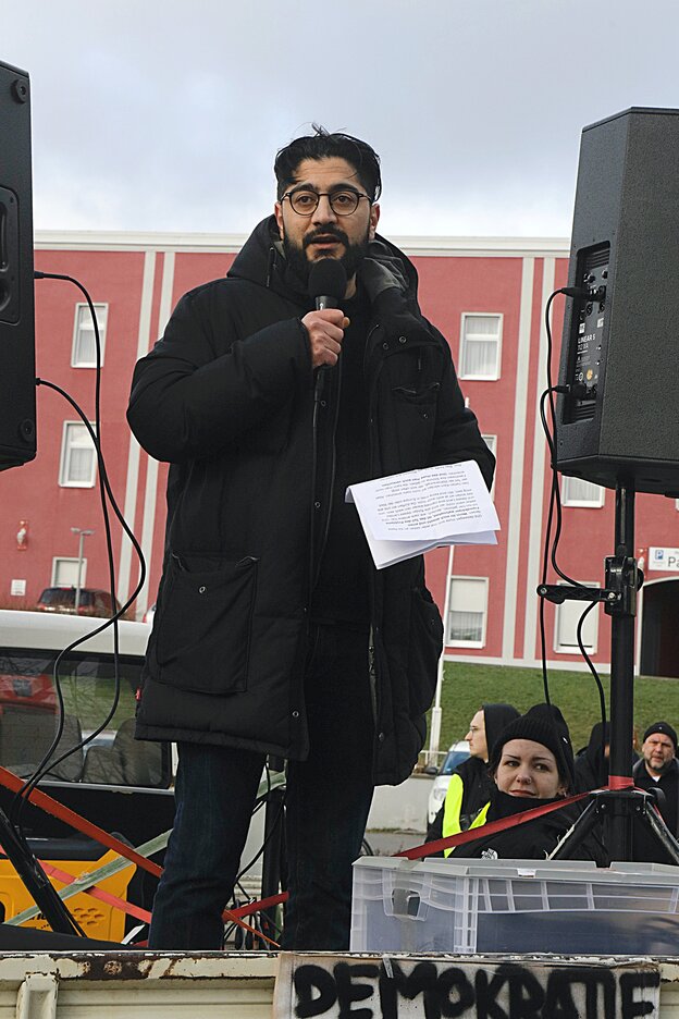 Ein Mann steht auf einer Bühne mit Mikrofon auf einer Demonstration in Frankfurt (Oder)