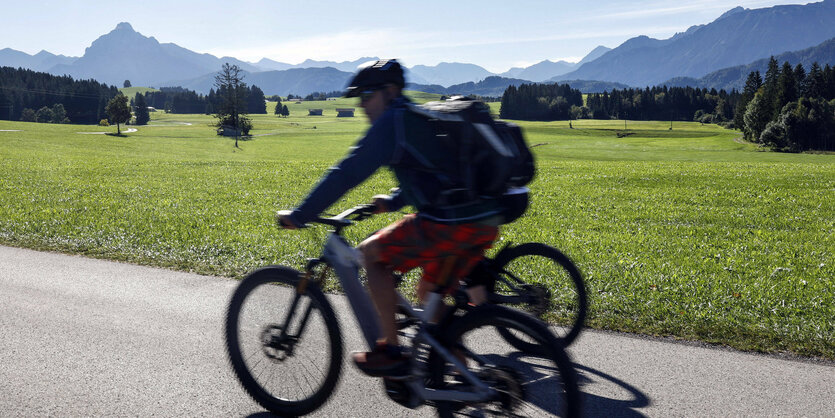 Radfahrer mit Bergen im Hintergrund.