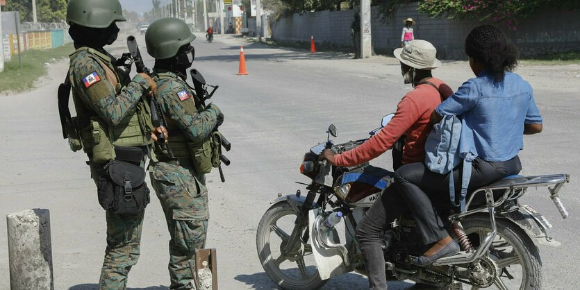 Soldaten und Motoradfahrer:innen auf eine rstraße.