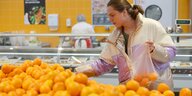 Szene im Supermarkt, Frauen am Obst- und Gemüsestand, eine Frau mit Einkaufstrolley begutachtet Bananen