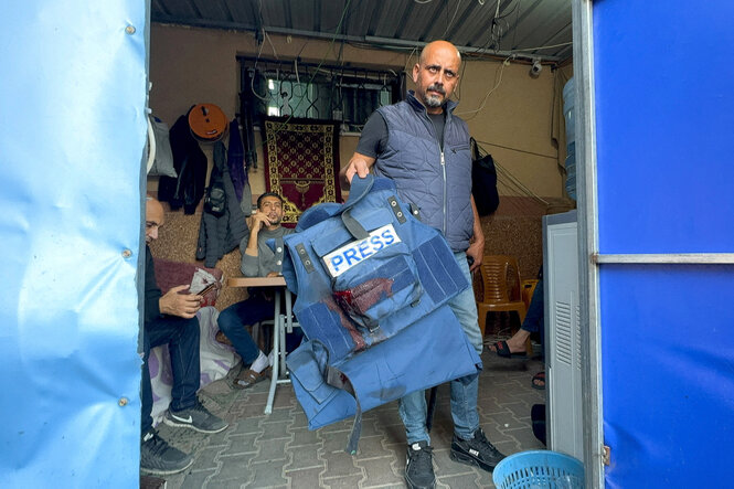 Ein Mann hält eine blutige schutzweste in die Kamera, die dem durch Bomben getöteten Al-Jazeera-Journalisten Wael Al-Dahdouh gehörte