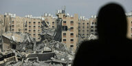 Eine Person schaut auf zerstörte Gebäude.