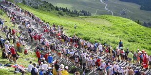 Zuschauer bilde bei einer Bergetappe ein Spalier, durch das die Radfahrer fahren müssen