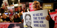 Ein Mann hält bei einer Demonstration ein Schild mit dem Foto eines jungen Mannes und der Aufschrift: "He has no time to wait. Bring him home alive!"