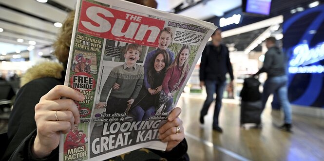 Eine Frau liest in der britischen zeitung "The Sun". Auf dem Titelbild ist ein Foto von Kate Middleton und ihren Kindern abgebildet