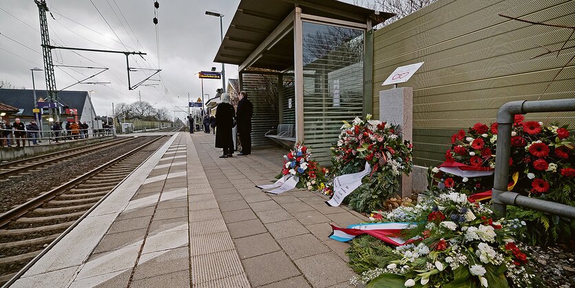 Graue Bahnsteigplatten und grüne Kränze neben einem Bahngleis