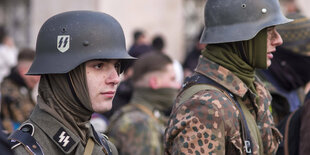 Menschen in Uniformen und Stahlhelm mit SS-Logo