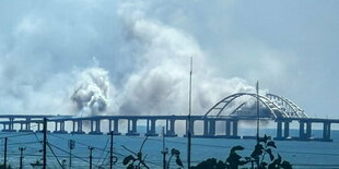 Dichter Qualm steigt hinter einer Brücke auf.