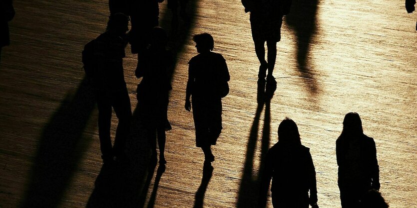 Silhouetten von Passanten bei Sonnenunteruntergang