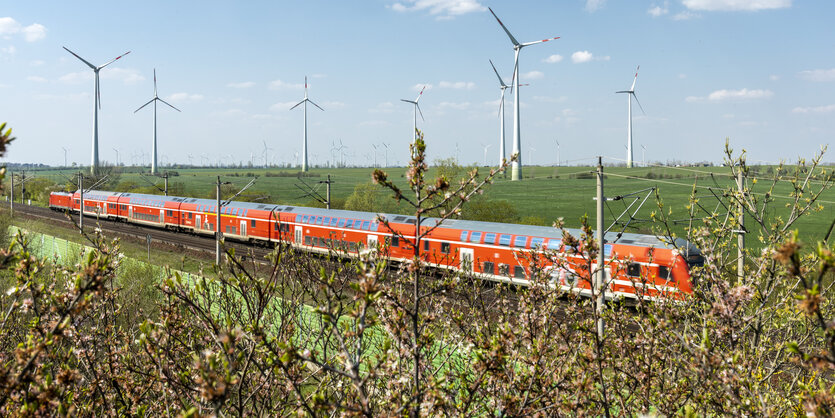 Ein Regionalexpress fährt durch eine Landschaft mit einem Windpark