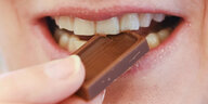 Eine Person beißt in ein Stück Schokolade