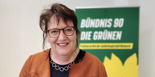 eine Frau vor einem Palakat der Grünen