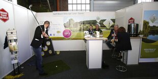 Ein Mann schwingt auf der Messe einen Golfschläger