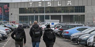 3 Männer gehen auf ein Gebäude mit Tesla Aufschrift zu