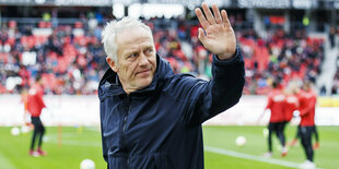 Christian Streich winkt auf dem Fussballfeld