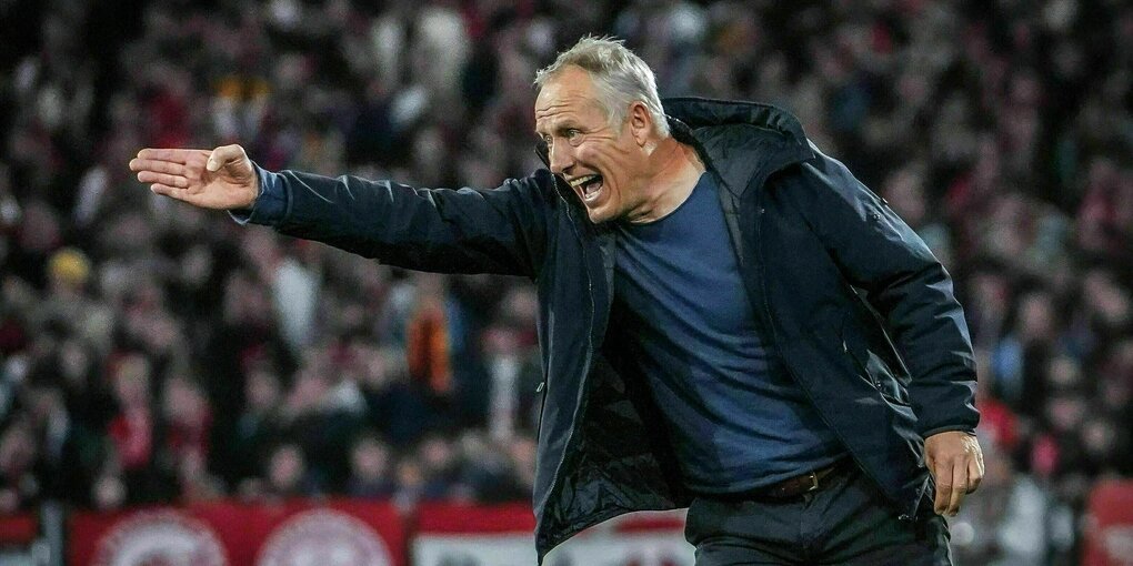 Trainer Christian Streich zeigt mit seinem Arm brüllend nach Links auf dem Fußballfeld