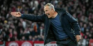 Trainer Christian Streich zeigt mit seinem Arm brüllend nach Links auf dem Fußballfeld