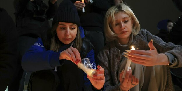 Zwei Frauen zünden Kerzen an nach dem Terroranschlag in Moskau