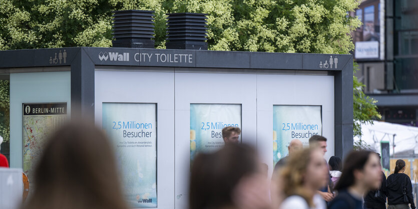 Passant:innen vor einem City-Klo in Berlin.