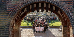 Menschen demonstrieren mit einem Transparent "Gegen jeden Antisemitismus - immer und überall!" durch das Holstentor in Lübeck.