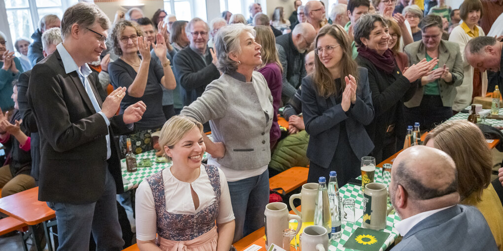 Applaus für Katharina Schulze , sie sitzt, eine Menge steht um Biertische