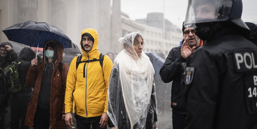 Demonstranten und Polizisten im Regen vor dem Brandenburger Tor