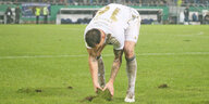 Ein Spieler des 1. FC Saarbrücken versucht ein Stück Rasen, das sich gelöst hat, wieder an seinen Ort zurückzulegen