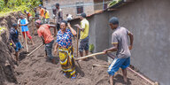 Eine Gruppe Menschen hackt die Erde in einem Graben auf hinter einem Haus