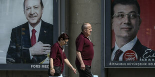 Ein Mann und eine Frau gehen an zwei Wahlplakaten vorbei: von dem des Präsidenten Erdogan gehen sie in Richtung des neuen Istanbuler Bürgermeisters Imamoglu