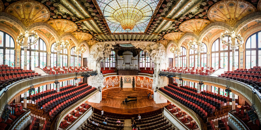 Blick in einen Konzertsaal mit Glasdach und Bogenfenstern, reich ornamentiert